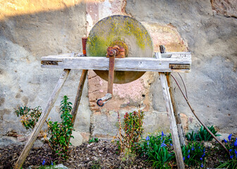 Historical stone wheel used for grinding grains in a rustic farming setting during daylight hours in an outdoor environment