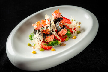 Gourmet sushi dish with salmon roe, seaweed, strawberries, and artistic sauces on a white plate against black background. Elegant plating, vibrant colors, and fine dining presentation.