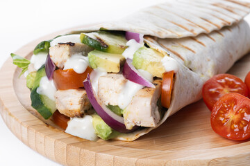 A delicious grilled chicken wrap with vegetables and avocado isolated on white background