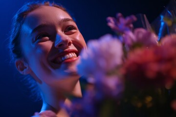 A ballerina beams with happiness as she receives a bouquet of colorful flowers following her impressive performance. The atmosphere is filled with excitement and admiration from the audience