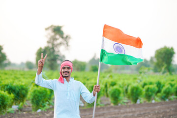 indian farmer waving national tricolor flag at agriculture field