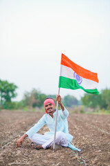 indian farmer waving national tricolor flag at agriculture field