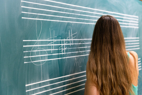 Music student studying notes on blackboard in music school