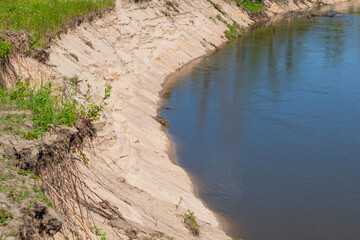 Eroded riverbank with exposed roots by a calm river bend
