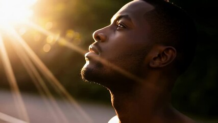 African american man looking up with hope as sunlight streams down, his face illuminated in a moment of peaceful contemplation, representing inspiration, faith and personal enlightenment