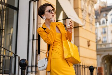 stylish elegant woman on shopping in city street wearing bright colorful yellow suit summer style