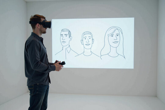 Man using virtual reality headset with projected avatars on wall  