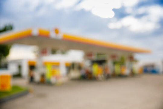 Defocused image of modern gas station with yellow and orange canopy under blue sky
