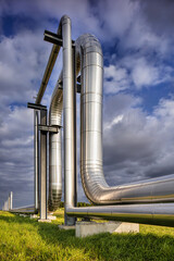 Massive shiny pipeline with dramatic clouds in industrial area 