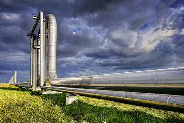 Massive shiny pipeline with dramatic clouds in industrial area 
