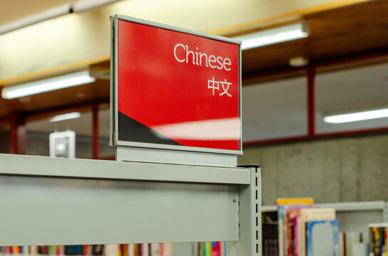 A bilingual library sign labeled "Chinese 中文" marks the section for Chinese language books. Concept of multilingual resources and cultural diversity in a community or educational institution.