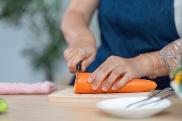 Healthy Cooking and Meal Prep. A person slicing a carrot in a modern kitchen setting.