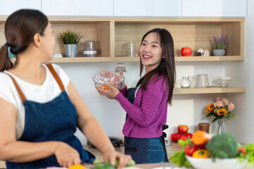 Cooking Together and Healthy Meal Prep. Two women laughing while preparing vegetables in a modern kitchen.