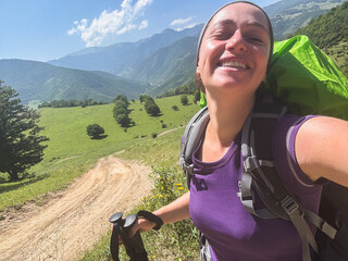 Hiking tourism adventure. Backpacker hiker woman taking selfie picture. Hiker girl lady tourist with backpack walking near mountain. Young happy woman enjoy hike trekking tourism active vacation