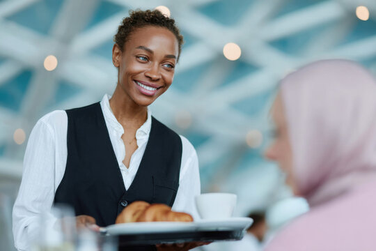 Smiling waitress serving breakfast to customer in restaurant