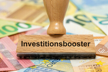 Ein Holzstempel ist beschriftet mit dem Aufdruck Investitionsbooster