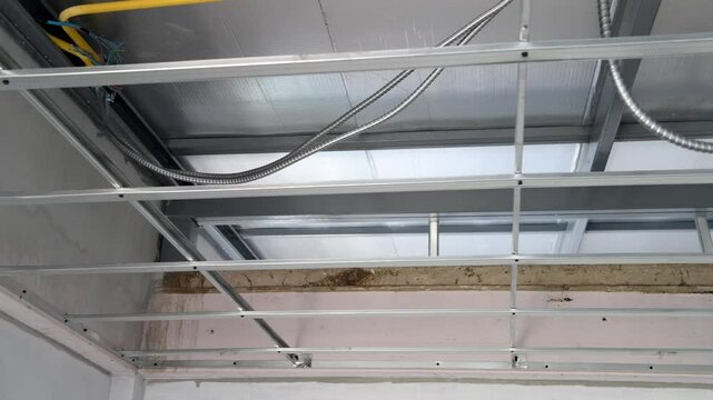 House interior renovation focusing on meticulous metal ceiling framework construction, with detailed look at complex electrical wiring installation process and grid system.