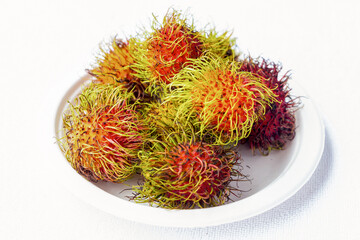 rambutan fruit Asia meets in the Thai market and Malaysia on a plate standing on a white background