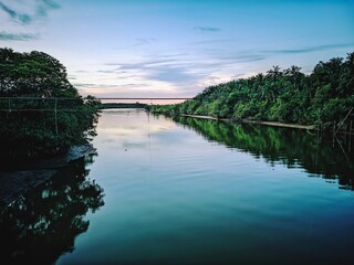 Serene Sunset Reflection on Calm River, Lush Green Banks