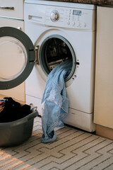 Washing clothes in a home laundry room with a washing machine and a basket of laundry