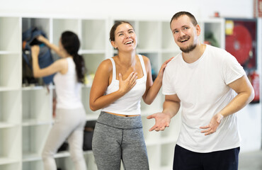 Man and woman, young rock climbers laugh and share stories in the changing room of a climbing wall...