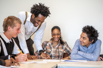 Teenage Students, Working Together. A teacher grading the group work of his class students. From a...