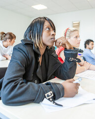 Teenage Students, Attentive Class. A pupil at her desk listening carefully and with interest to her teacher. From a series of related images.
