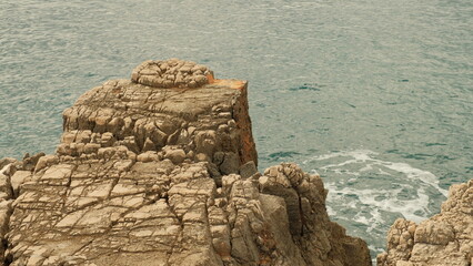 Weathered limestone cliff with sharp geometric textures and deep cracks overlooking the Adriatic...