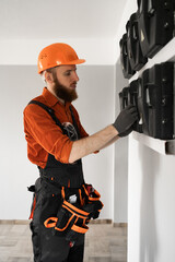 Bearded male electrician works at construction site with switchboard