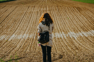 Woman standing on a spring plowed field, fresh rural earth ready for new crop season