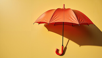 Red umbrella casting shadow on yellow background in sunlight  