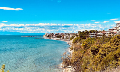Coastal view of a Mediterranean seaside town with turquoise water, lush greenery, and clear blue...