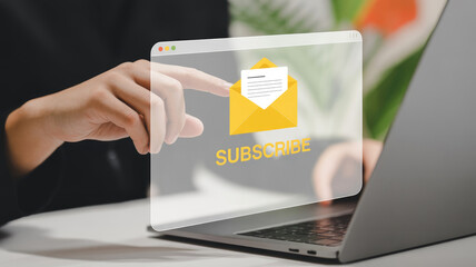A laptop screen with a yellow envelope and a hand pointing to the word "subscribe" on the screen