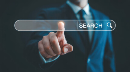 A man in a suit is pointing to a search bar on a computer screen. Concept of professionalism and focus, as the man is likely working on a task that requires him to search for information