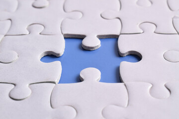 White puzzle with missing piece on blue background, closeup