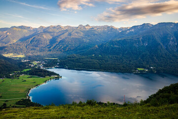 view from above of Lake Bohinj, illuminated by the setting sun, and the mountains on the opposite shore