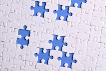 White puzzle with missing piece on blue background, top view