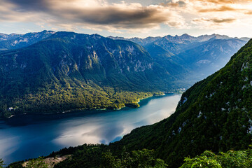 view from above of Lake Bohinj, illuminated by the setting sun, and the mountains on the opposite shore