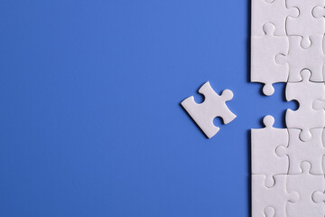 White puzzle pieces on blue background. Flat lay. Top view