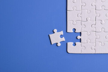 White puzzle pieces on blue background. Flat lay. Top view
