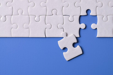 White puzzle pieces on blue background. Flat lay. Top view