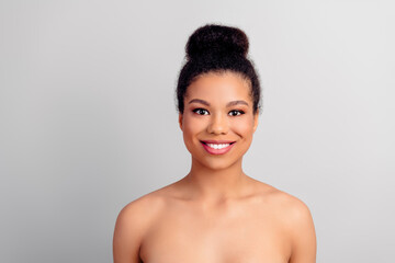 Young woman with natural beauty and stylish updo hairstyle posing on a light neutral background