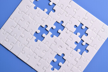 White puzzle with missing piece on blue background, top view