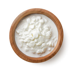 Chunky cottage cheese in a wooden plate on a white. Top view