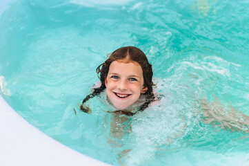 Cheerful, funny girl, child teenager swims in the pool, grimacing, smiling. Photo, portrait.