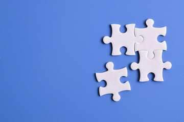 Four puzzle pieces on blue background. The concept of finding the right solutions in teamwork.
