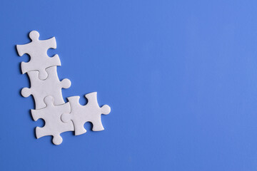 Four puzzle pieces on blue background. The concept of finding the right solutions in teamwork.