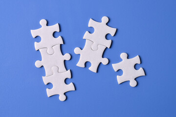 White puzzle pieces on blue background, top view