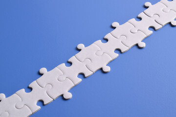 White puzzle pieces forming a line on blue background