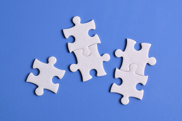White puzzle pieces on blue background, top view